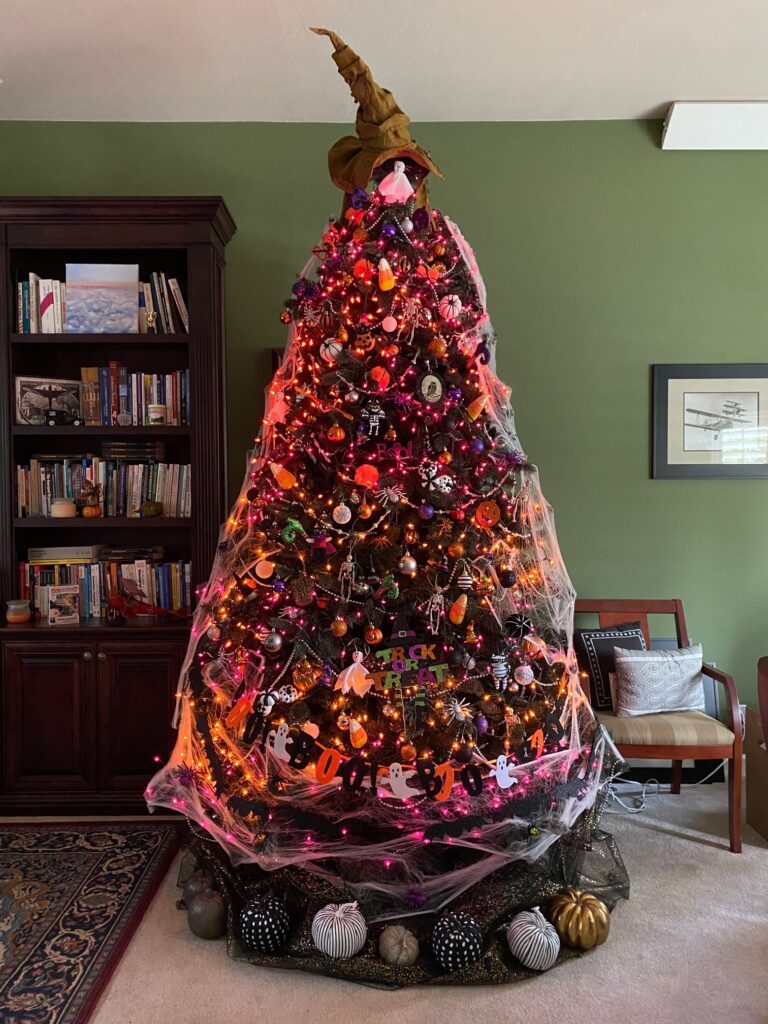 Christmas tree decorated for Halloween with Sorting Hat topper