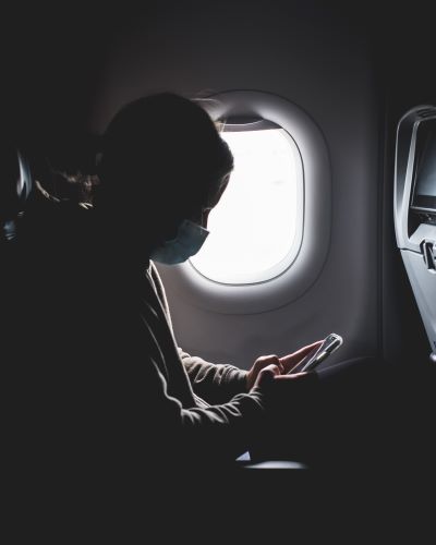 Image of airline passenger wearing a mask and looking at her phone